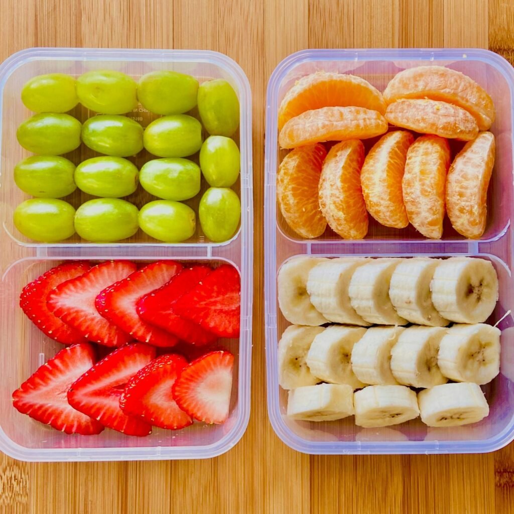 Assorted sliced fruits including strawberries, bananas, and oranges in containers.