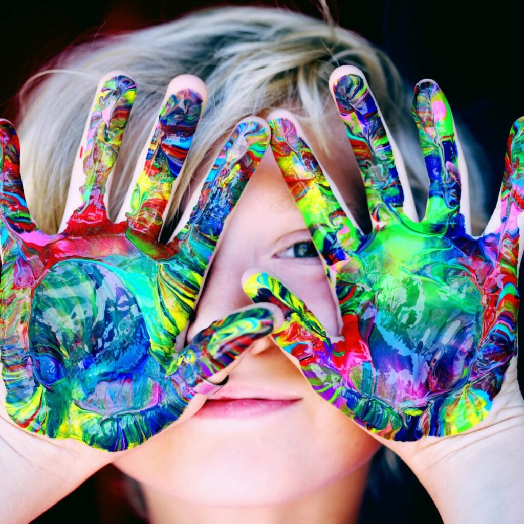 Vibrant close-up of a child's hands covered in colorful paint, expressing creativity and fun.